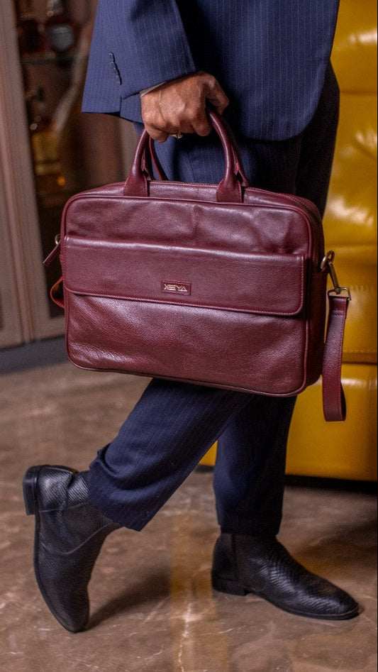 Person holding a maroon leather briefcase with a blurred background